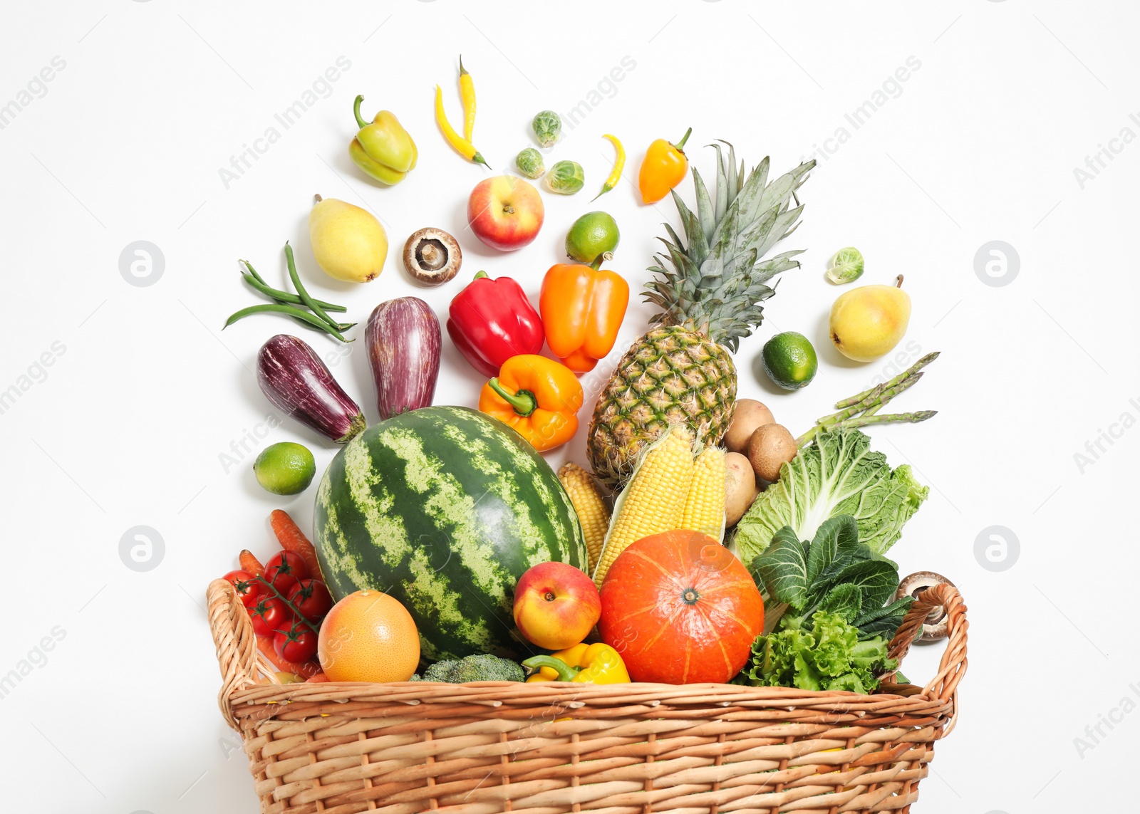 Photo of Basket with assortment of fresh organic fruits and vegetables on white background, top view