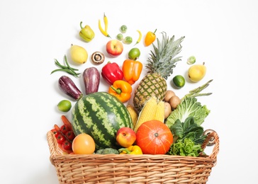 Photo of Basket with assortment of fresh organic fruits and vegetables on white background, top view