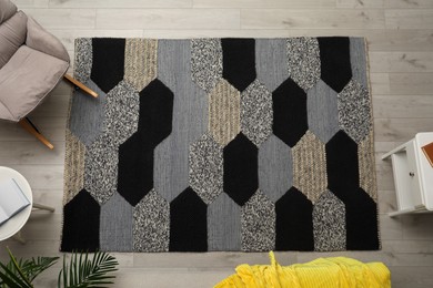 Photo of Carpet with geometric pattern on wooden floor in room, top view