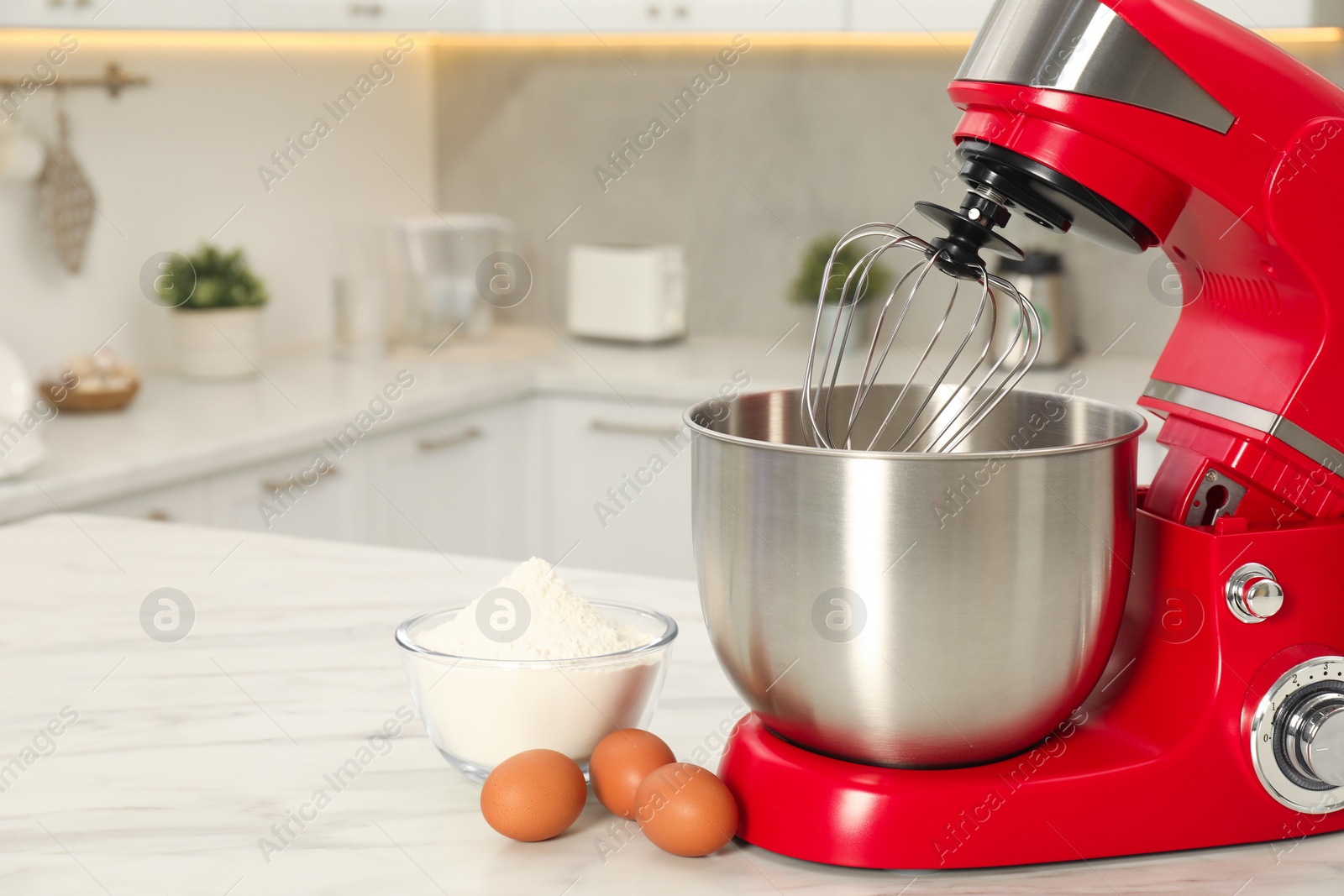 Photo of Modern red stand mixer, eggs and bowl with flour on white marble table in kitchen, space for text