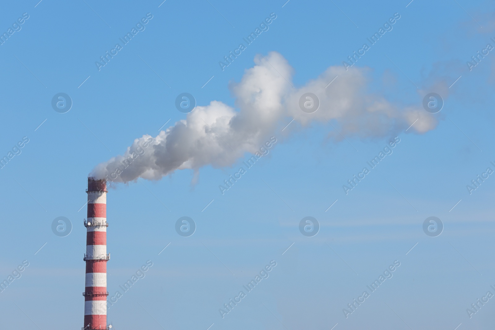 Photo of Polluting air with smoke from industrial chimney outdoors against blue sky. CO2 emissions