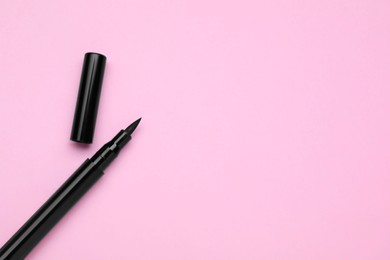 Eyeliner marker on pink background, top view with space for text. Makeup product