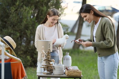 Photo of Women shopping at table in yard. Garage sale