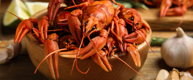 Image of Delicious red boiled crayfishes on table, closeup. Banner design