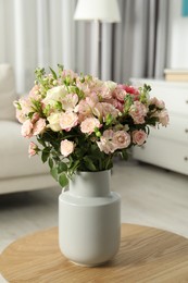 Photo of Beautiful bouquet of fresh flowers in vase on wooden coffee table indoors