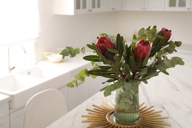 Photo of Bouquet with beautiful protea flowers on table in kitchen, space for text. Interior design