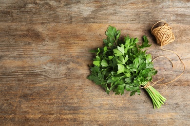 Photo of Bunch of fresh green parsley and twine on wooden background, flat lay. Space for text