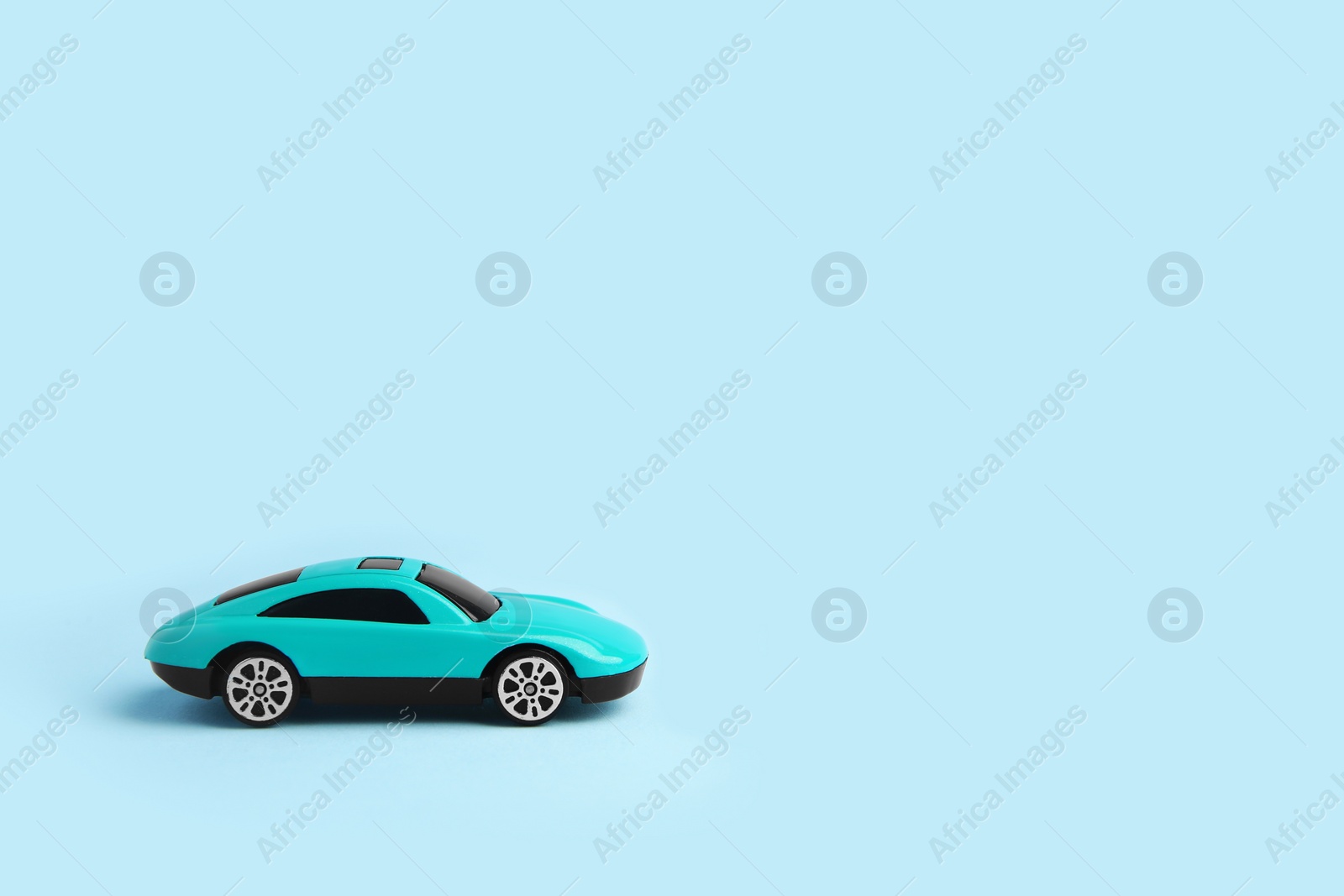 Photo of One bright car on light blue background, space for text. Children`s toy