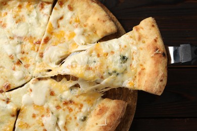 Photo of Taking piece of delicious cheese pizza at wooden table, top view