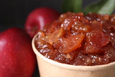 Delicious apple jam in paper cup and fresh fruits, closeup