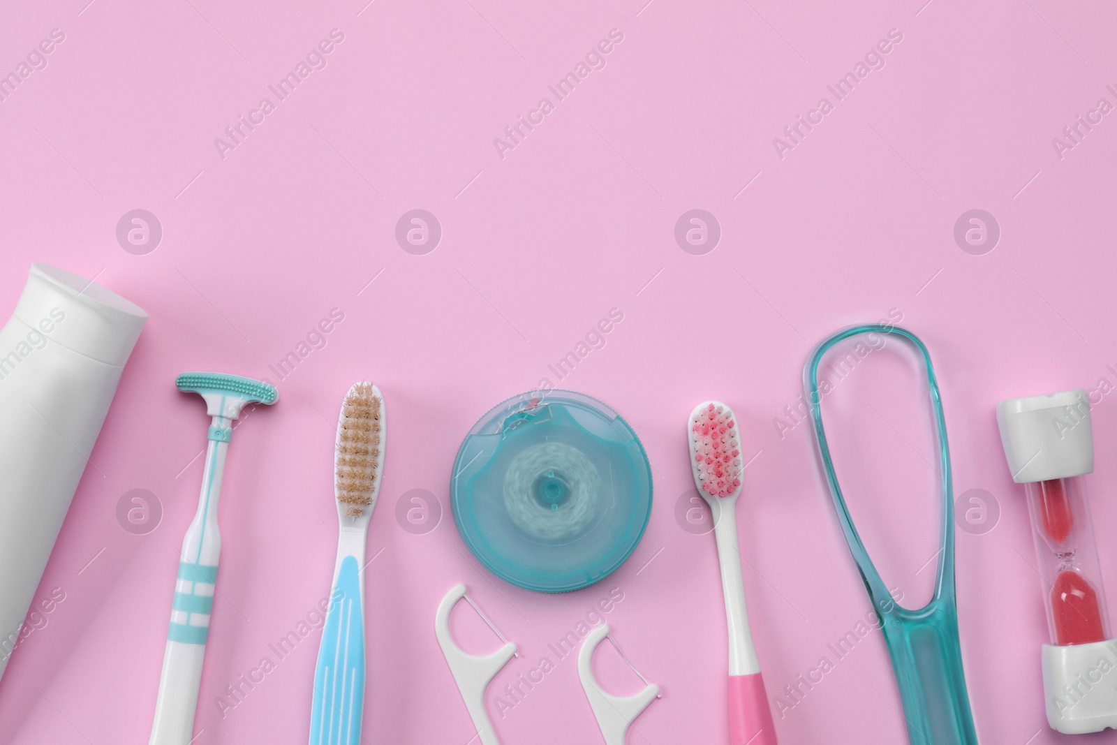 Photo of Flat lay composition with tongue cleaners and teeth care products on pink background, space for text