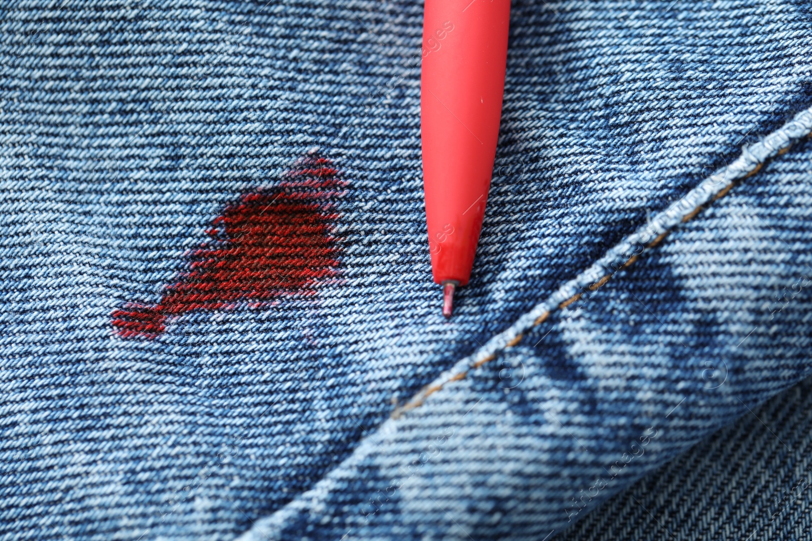 Photo of Pen and stain of red ink on jeans, closeup