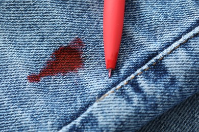 Pen and stain of red ink on jeans, closeup