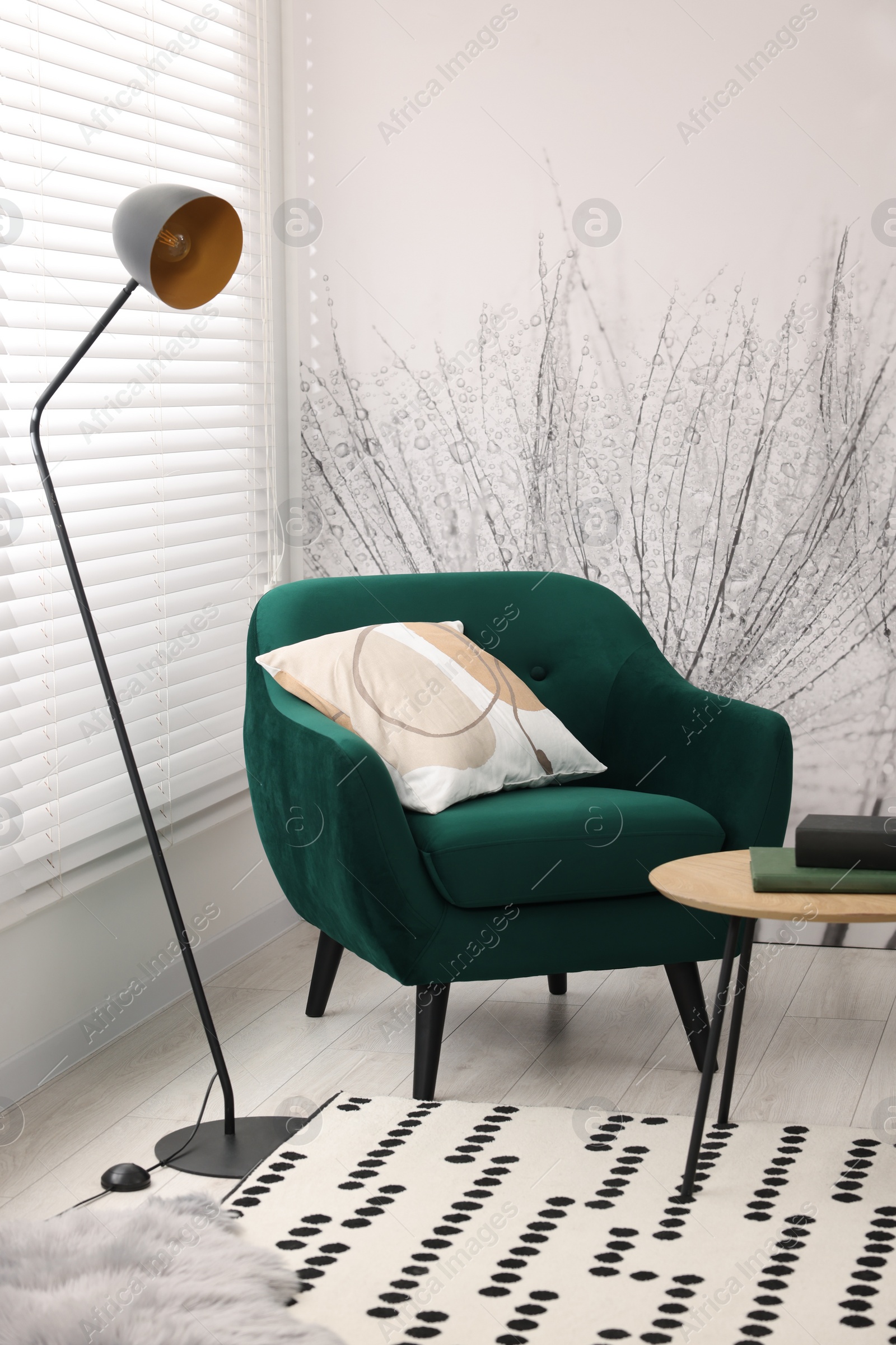 Photo of Comfortable armchair, lamp and side table in stylish room