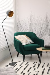 Comfortable armchair, lamp and side table in stylish room