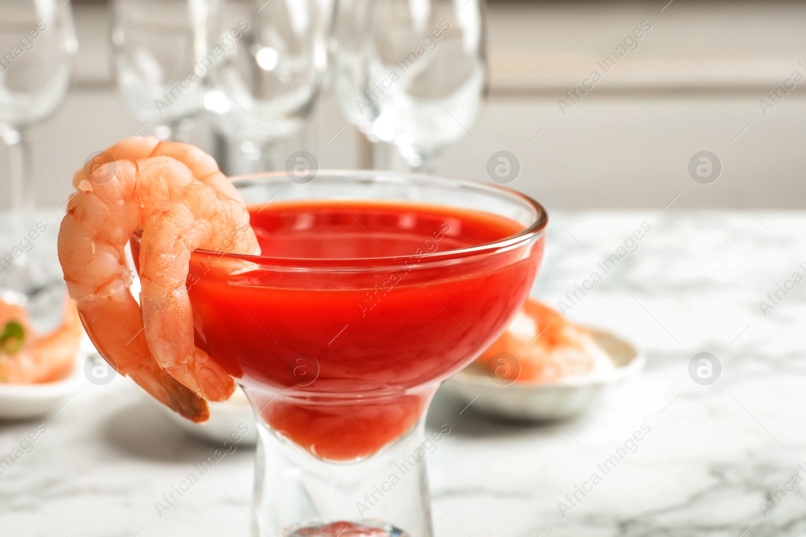 Photo of Glass with boiled shrimps and tomato sauce on table