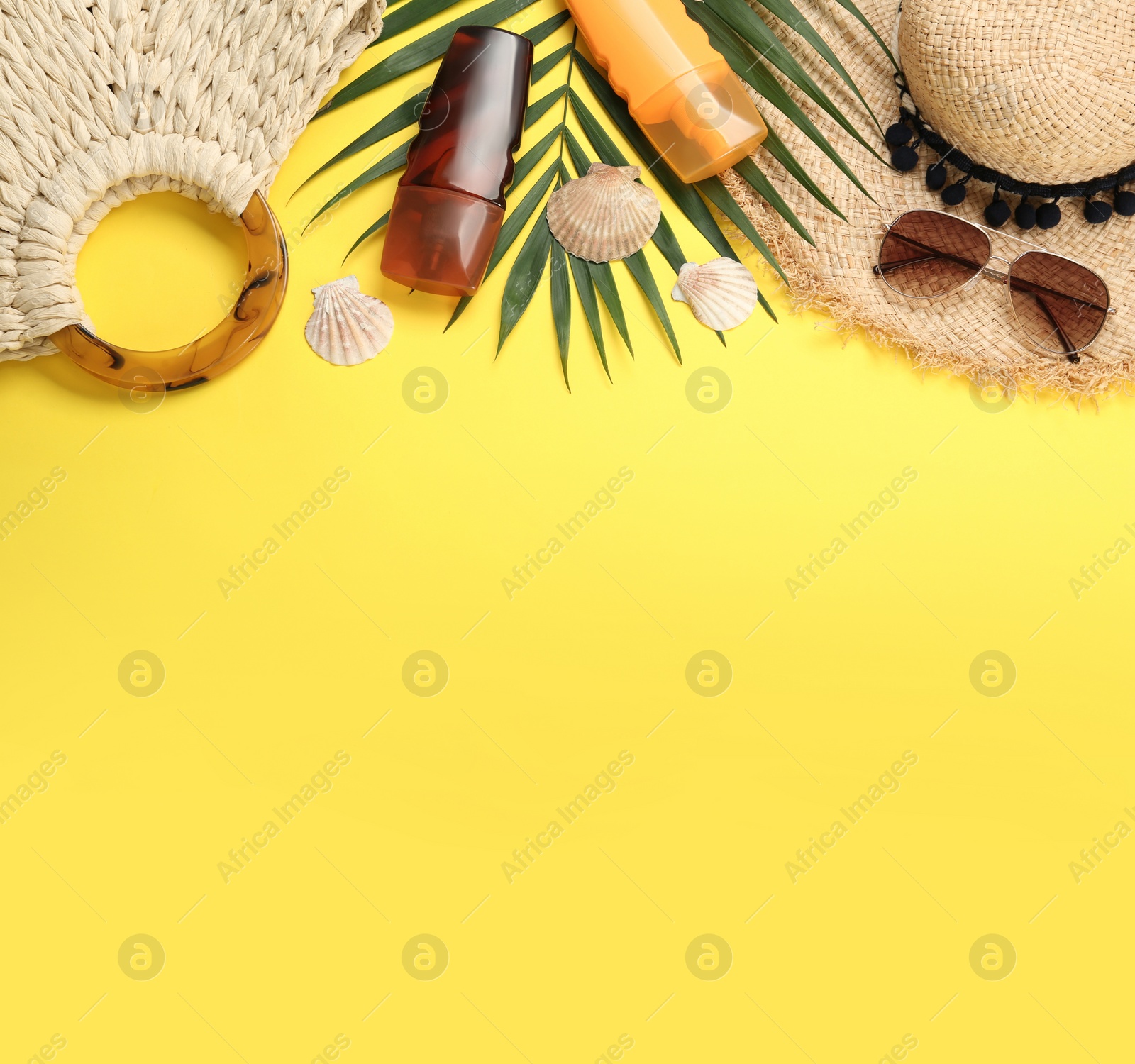 Photo of Sun protection products and beach accessories on yellow background, flat lay. Space for text