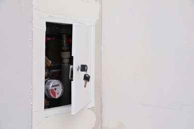 Water meter hidden in niche on white wall