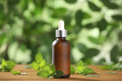 Photo of Glass bottle of nettle oil with dropper and leaves on wooden table against blurred background