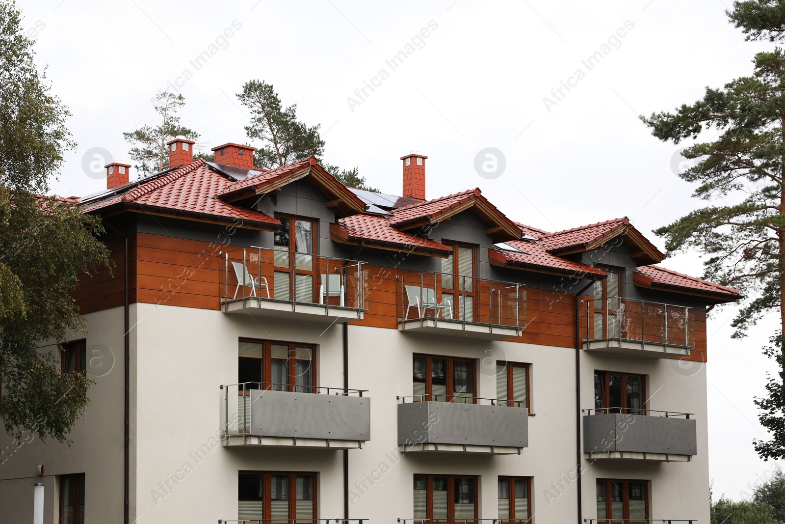 Photo of Beautiful beach house with balconies and trees outdoors