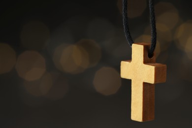 Photo of Wooden Christian cross against blurred lights, closeup. Space for text