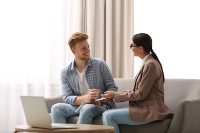 Young man signing contract with female insurance agent in office