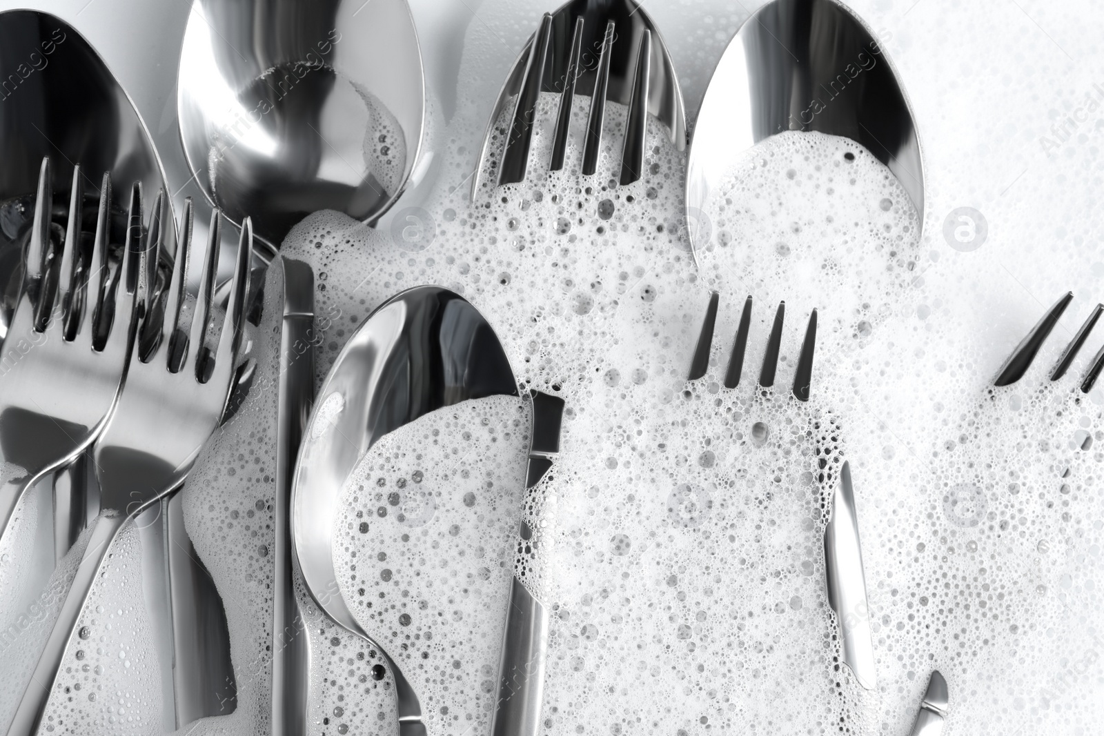 Photo of Many forks and spoons in foam, flat lay. Washing silverware