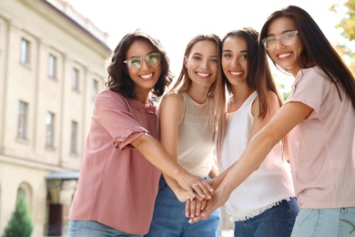 Happy women putting hands together outdoors. Girl power concept