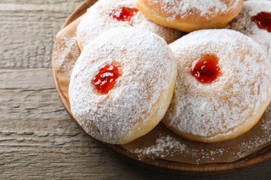 Photo of Delicious donuts with jelly and powdered sugar on wooden table, closeup