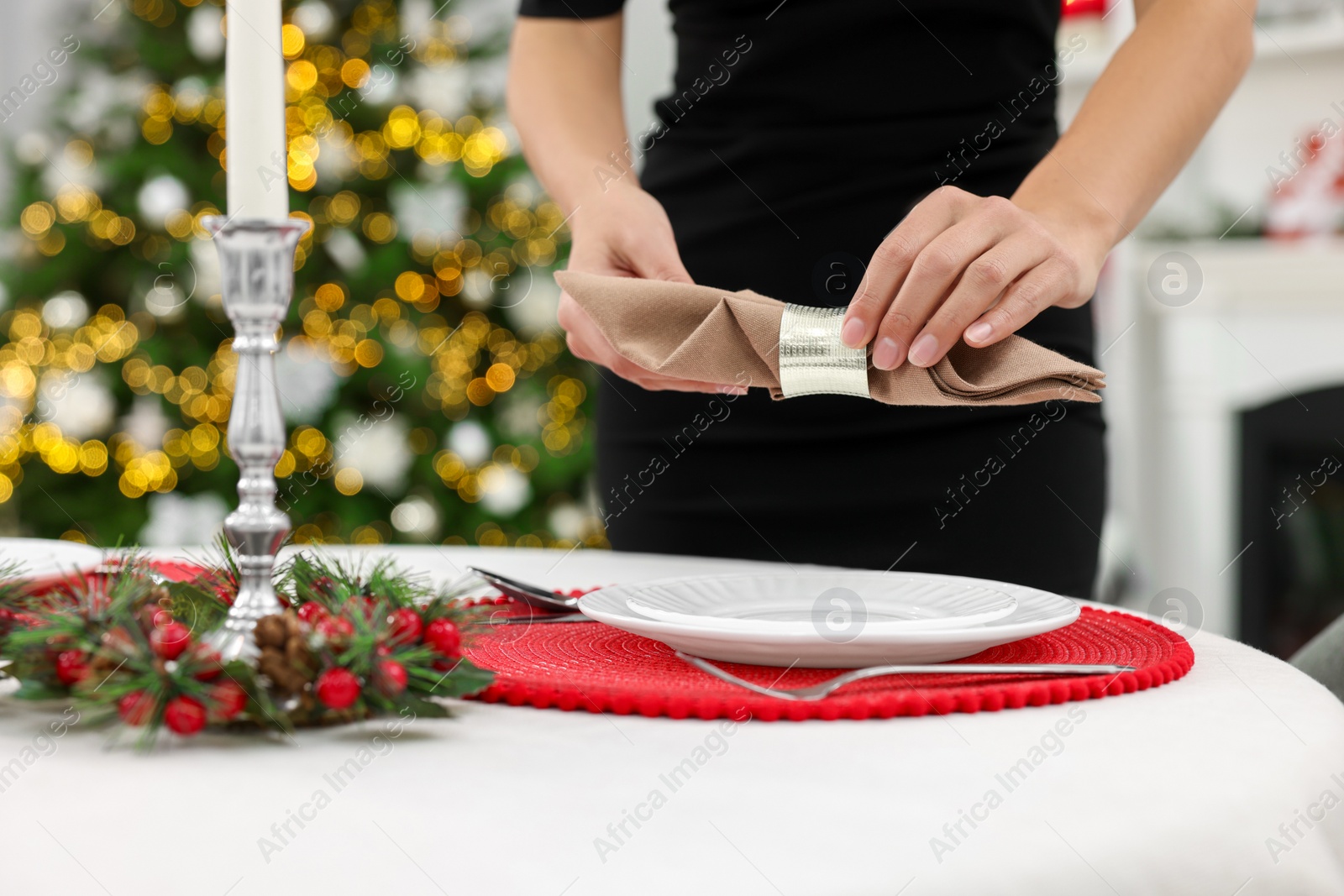 Photo of Woman setting table for Christmas celebration at home, closeup