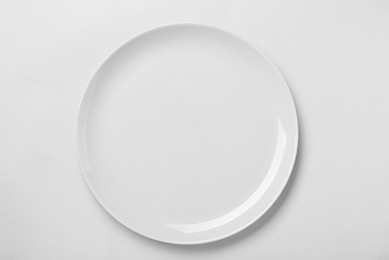 Empty ceramic plate on white background, top view