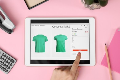 Woman with tablet shopping online on pink background, top view