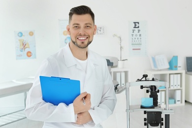Photo of Ophthalmologist with modern equipment and clipboard in clinic