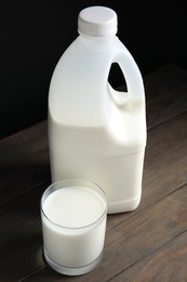 Photo of Gallon bottle and glass of milk on wooden table