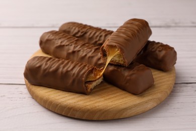 Photo of Tasty chocolate bars with caramel on white wooden table