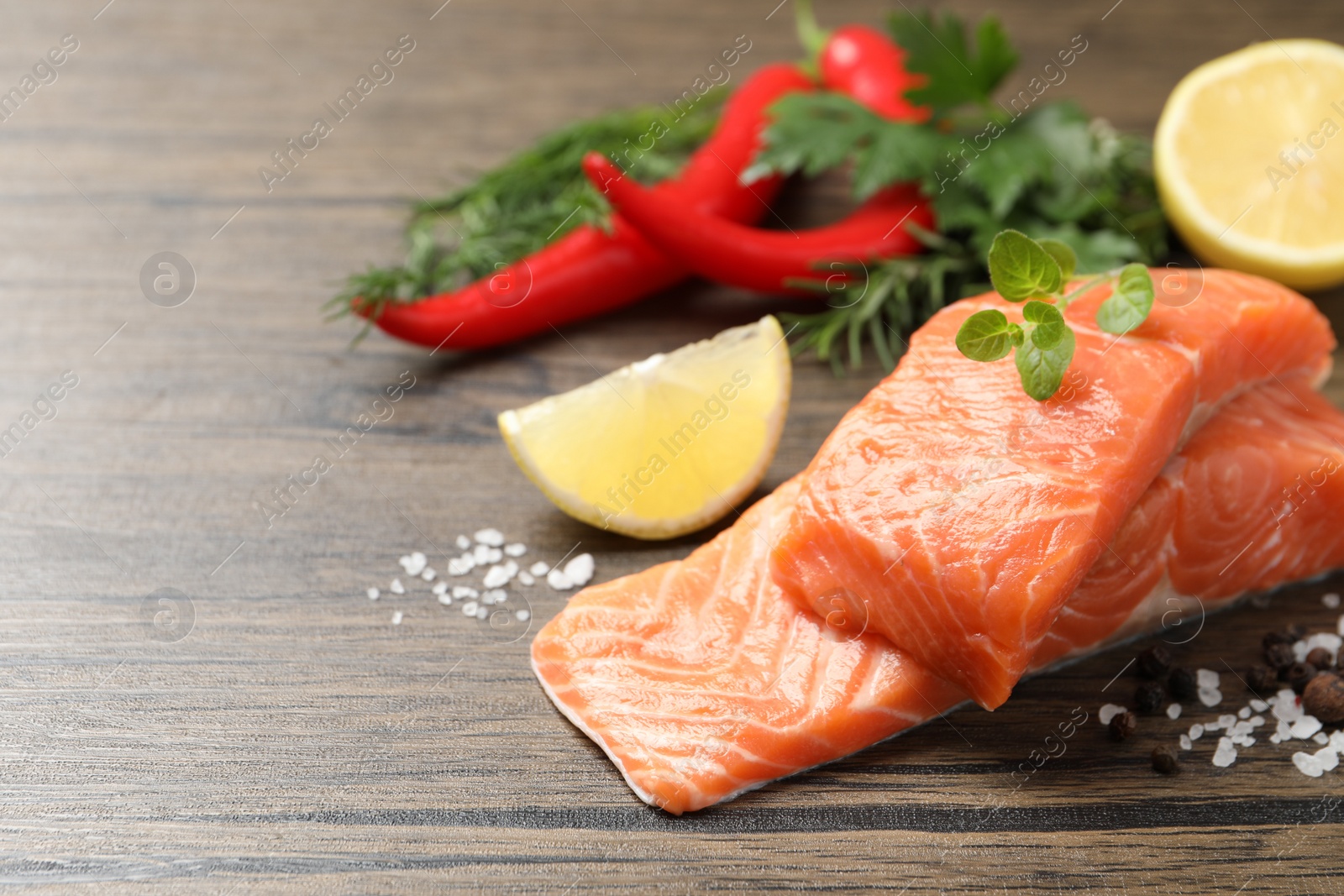 Photo of Fresh salmon and ingredients for marinade on wooden table. Space for text