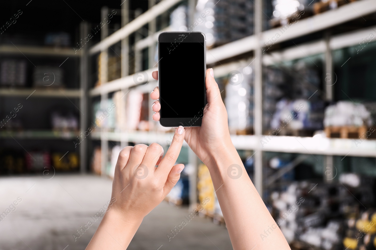 Image of Wholesale trading. Woman using WMS app on smartphone at warehouse, closeup 