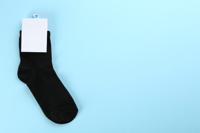 Photo of Pair of black cotton socks on light blue background, top view. Space for text