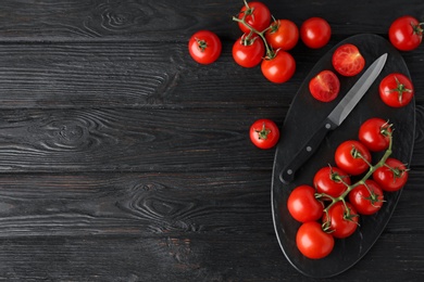 Photo of Flat lay composition of fresh whole and cut tomatoes on dark wooden table. Space for text