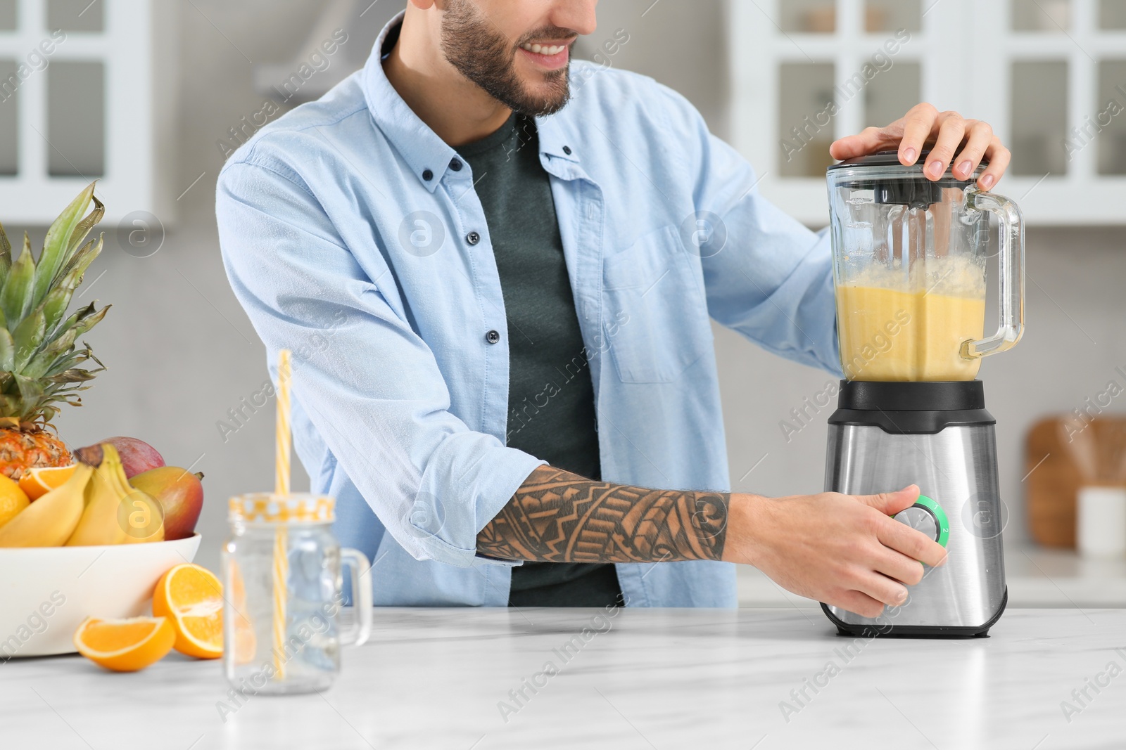 Photo of Man preparing ingredients for tasty smoothie at white marble table in kitchen, closeup