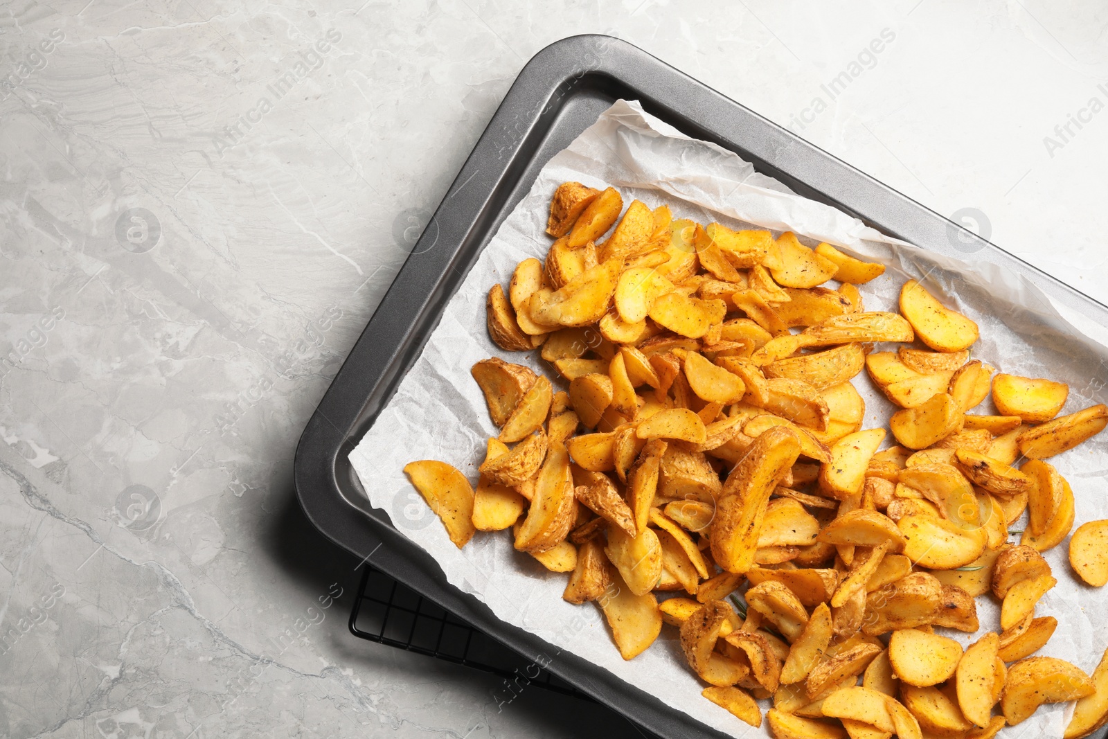 Photo of Sheet pan with delicious oven baked potatoes on marble background, flat lay. Space for text