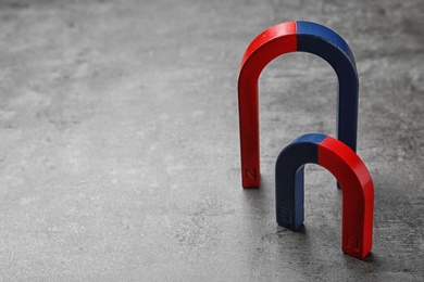 Photo of Red and blue horseshoe magnets on grey background. Space for text