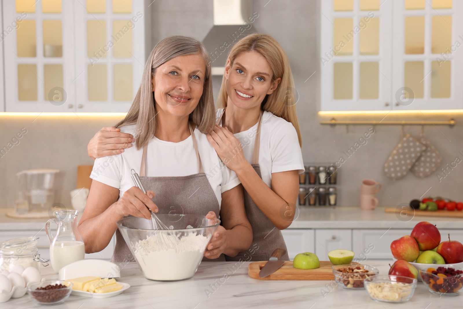 Photo of Happy mature mother and her daughter cooking together at kitchen