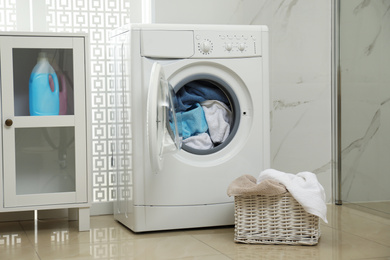 Photo of Modern washing machine with towels in bathroom