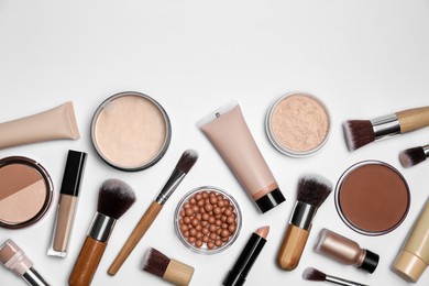 Photo of Face powders and other makeup products on white background, flat lay