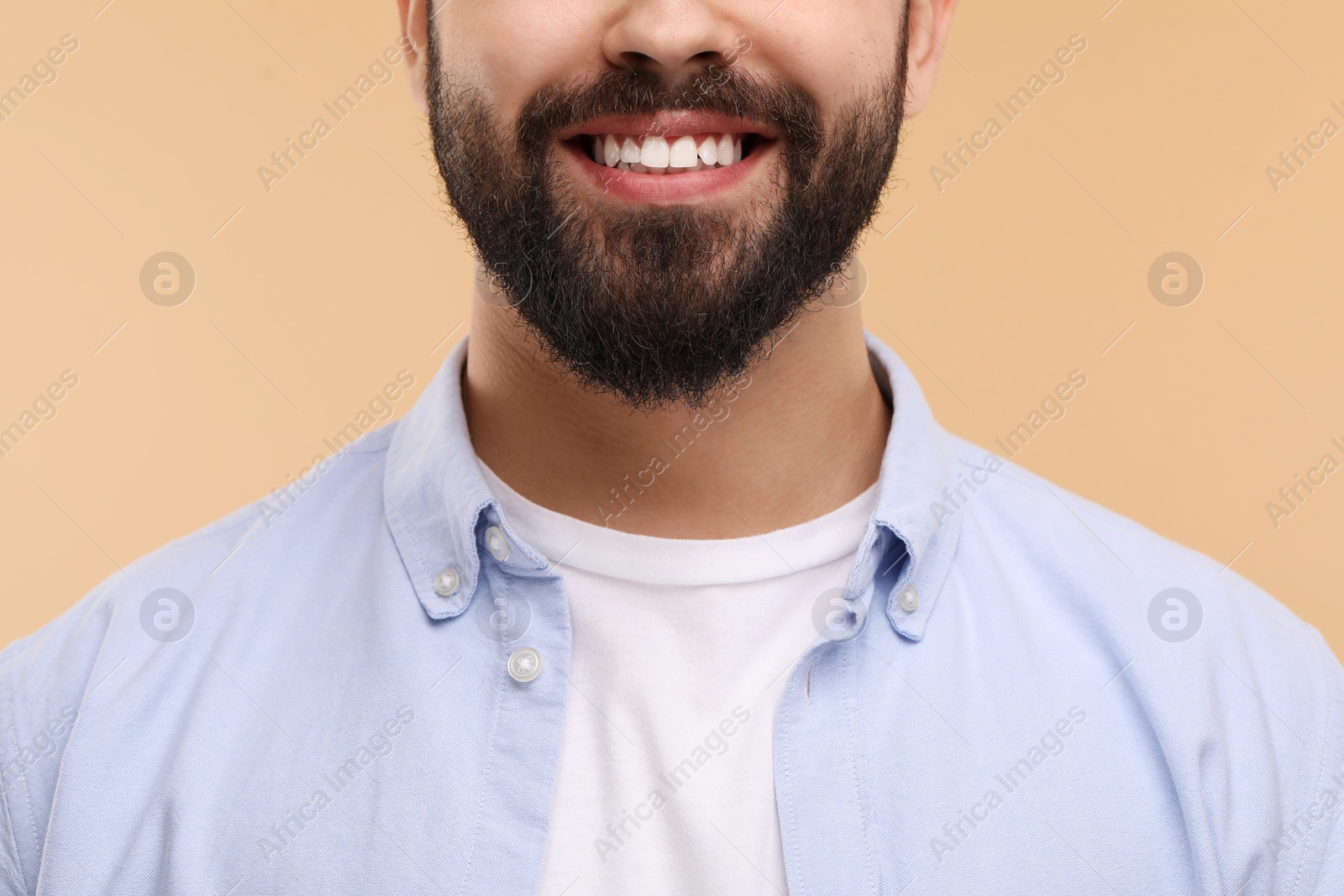 Photo of Man with clean teeth smiling on beige background, closeup