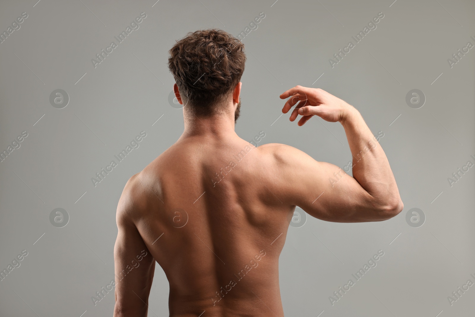 Photo of Man with muscular body on light grey background, back view