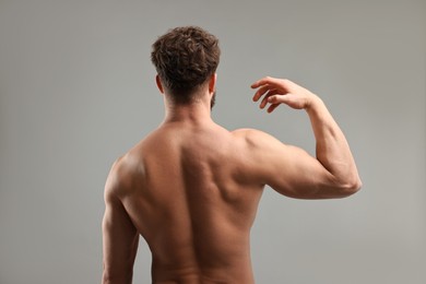 Man with muscular body on light grey background, back view