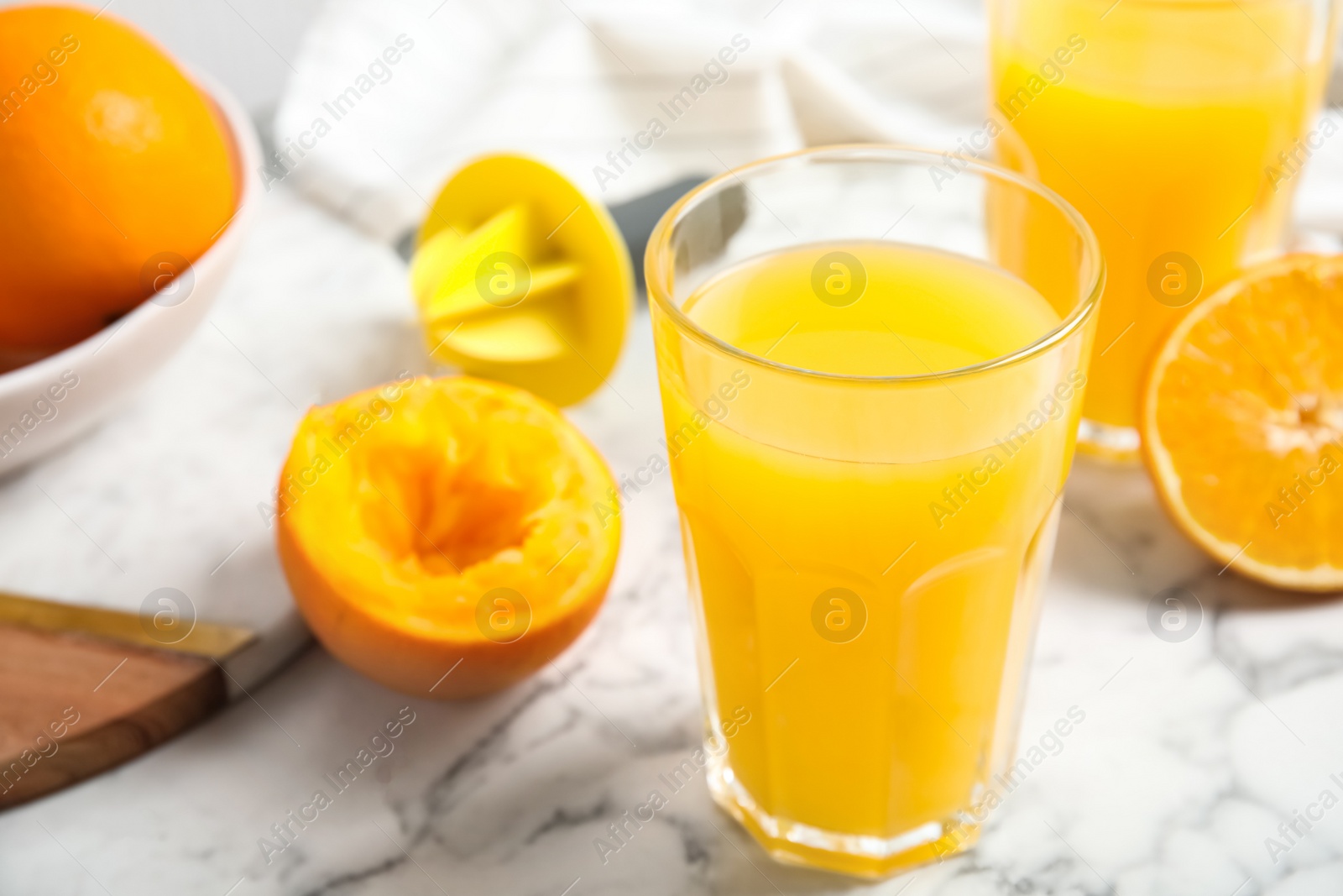 Photo of Fresh ripe orange, juice and reamer on white marble table, closeup. Space for text