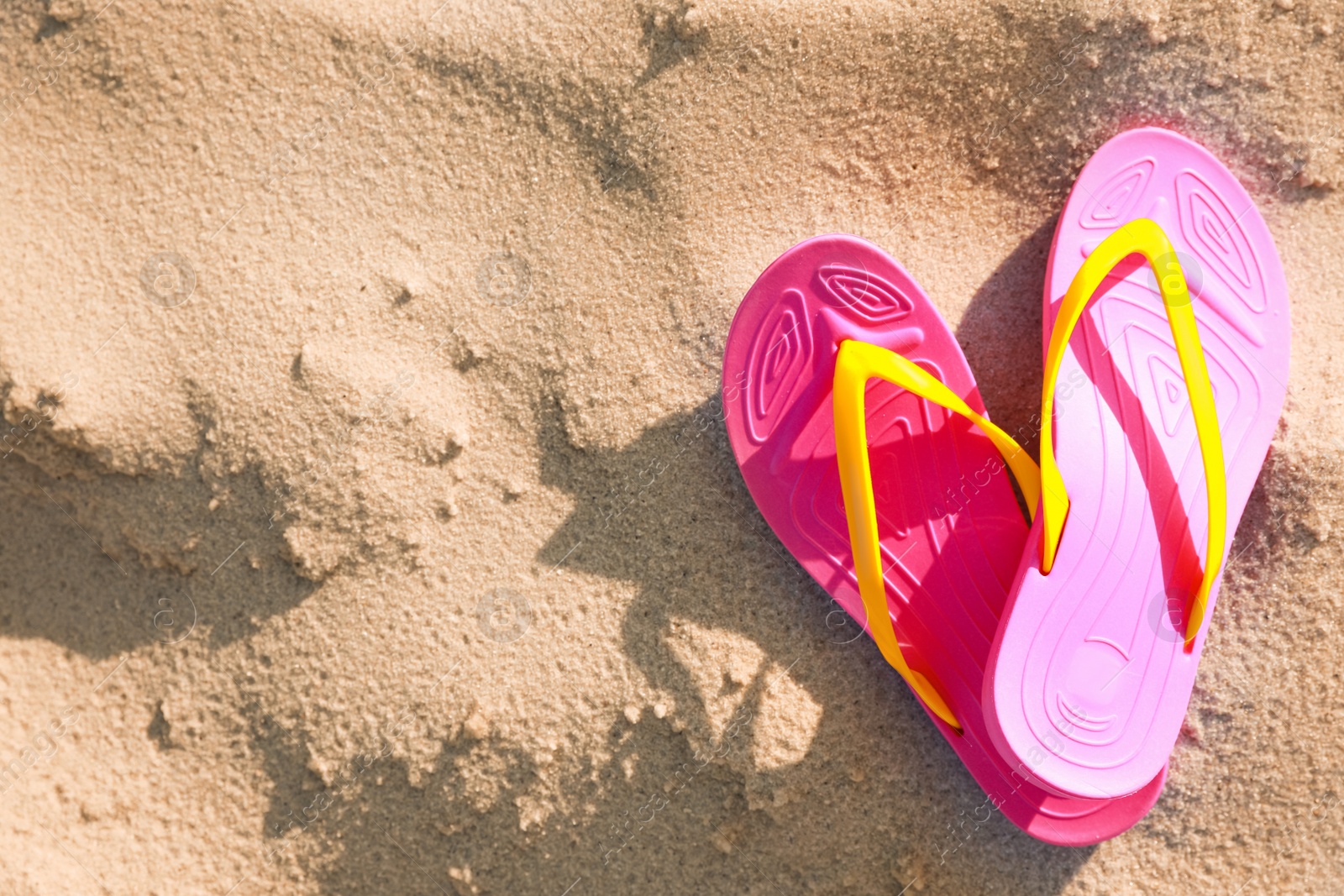 Photo of Stylish flip flops on beach, top view. Space for text